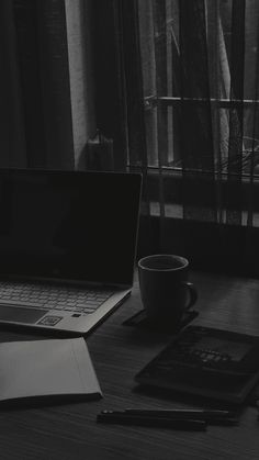 an open laptop computer sitting on top of a wooden desk next to a cup of coffee