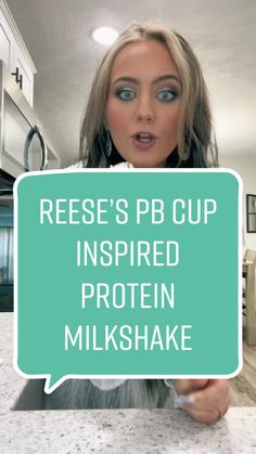 a woman holding up a sign that says reese's pb cup inspired protein milkshake