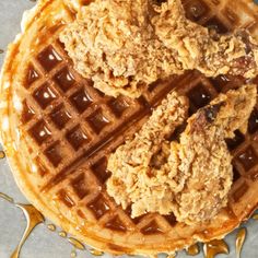 two fried chicken and waffles on top of each other with syrup drizzled around them