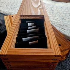 a wooden box filled with lots of black labels on top of a bed next to a white comforter