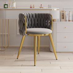 a pink chair with gold legs in front of a white counter top and sink area