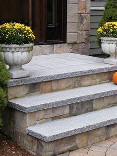 an orange pumpkin sitting on the steps of a stone house in front of some bushes