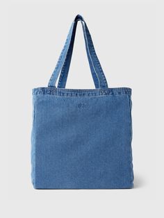 a denim tote bag is shown on a white background, with the handles down