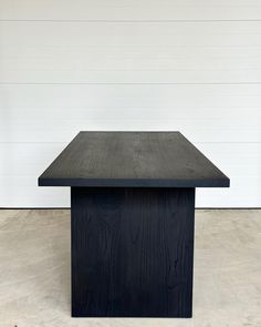 a black square table sitting on top of a white floor next to a wooden wall