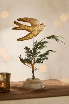 a gold bird decoration sitting on top of a wooden table next to a candle holder