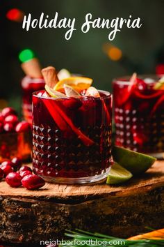 two glasses filled with holiday sangria sitting on top of a wooden table