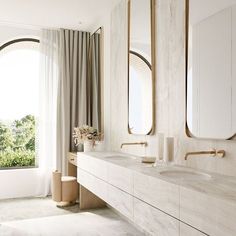 a bathroom with two sinks and mirrors on the wall next to a window overlooking trees