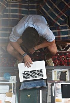 a man sitting on top of a couch next to a laptop computer and other items