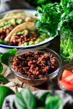 two bowls filled with food sitting on top of a table next to other foods and vegetables