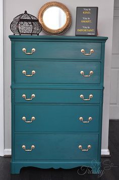 a blue dresser with gold handles and knobs in a room next to a mirror