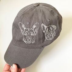 a person holding a hat with two dogs embroidered on the front and back of it