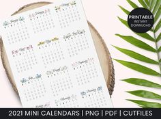 a printable 2021 mini calendar on top of a piece of wood next to leaves