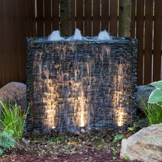 a water fountain in the middle of a garden with rocks around it and plants growing next to it