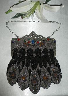 "Such a brilliant evening bag that was surely an upscale accessory for a refined lady of her day. This is a heavy bag, intricately beaded with a very ornamental frame, faux jewels of various colors adorning the one side. The bag itself is 8.25\" from the top of the frame to the bottom of the purse, add 6\" more for the chain handle drop. It is just a pinch over 7\" at the widest point and the frame is 6\" wide. The purse is 100 years old, so some of the beads have fallen away, as you can see. As Vintage Pouch Bag For Party, Vintage Clutch Shoulder Bag For Party, Vintage Handheld Bag For Party, Vintage Rectangular Party Bag, Black Victorian Bag For Vintage Events, Victorian Style Black Bag For Vintage Events, Vintage Silver Shoulder Bag For Party, Antique Silver Bag For Party, Vintage Embellished Rectangular Bag