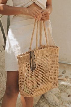 a woman is holding a straw bag in her hands