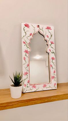 a mirror sitting on top of a wooden shelf next to a potted succulent