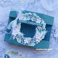 a close up of a christmas card on a marble surface with paper flowers and leaves