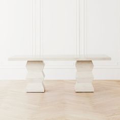 a white table sitting on top of a hard wood floor next to a white wall