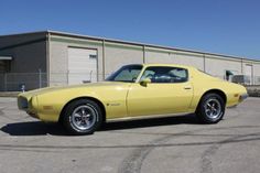 a yellow car is parked in front of a storage building with an empty parking lot