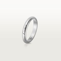 a white gold wedding ring with the word love engraved on it's side, in front of a plain background