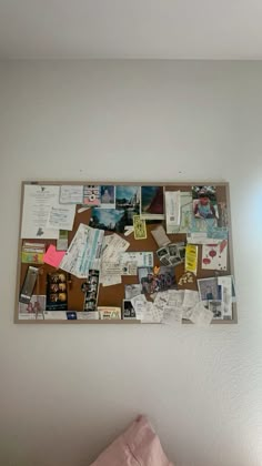 a bulletin board is covered with papers and other things on the wall above a bed