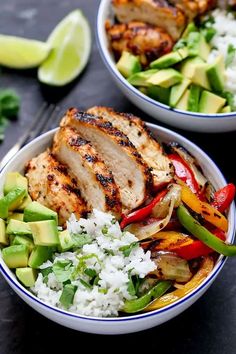 two bowls filled with chicken, rice and veggies next to lime wedges