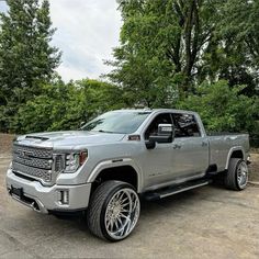 a silver truck parked in front of some trees