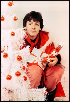 a man sitting next to a white christmas tree