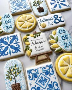 decorated cookies with blue and yellow designs are on a white countertop, next to a plaque that reads welcome to mellie's bridal shower