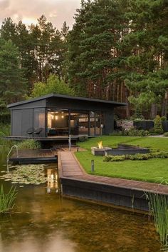 there is a small house on the side of the water in the park with trees around it