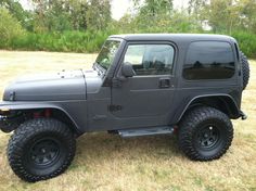 a gray jeep parked on top of a grass covered field