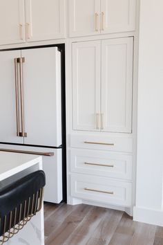 a kitchen with white cabinets and gold handles