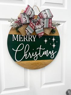 a merry christmas sign hanging on the front door with burlocks and bows attached to it