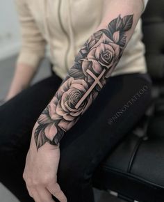 a person with a cross and roses tattoo on their arm