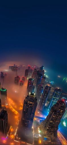 an aerial view of a city at night with lights and fog in the air,