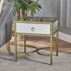 a white and gold end table sitting on top of a rug next to a couch