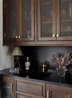 a kitchen with wooden cabinets and black counter tops, along with vases filled with flowers