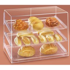 three tier acrylic bakery display case with breads and pretzels in it