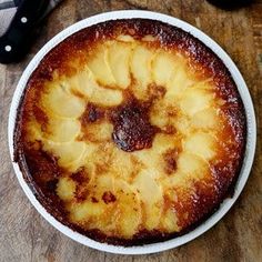 a pineapple upside down cake sitting on top of a wooden table next to a knife