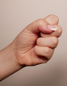 a hand holding something in it's palm with white and pink nail polish on it