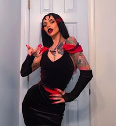 a woman in a black dress with tattoos on her arms