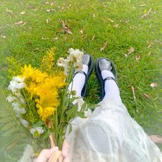 a person holding flowers in their hands on the grass