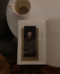 an open book on a table next to a cup of coffee