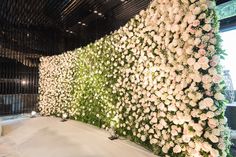 the wall is covered with white flowers and greenery