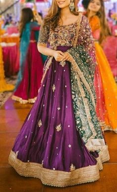 a woman in a purple and green lehenga is standing on the dance floor