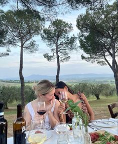 two women sitting at a table with wine glasses