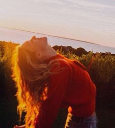 a woman flying a kite on top of a lush green field next to the ocean