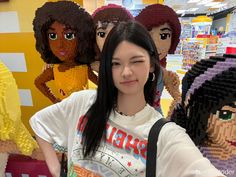 a woman taking a selfie in front of legos at a store with other people behind her