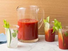 three pitchers and two glasses filled with red liquid