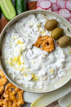 a bowl filled with dip surrounded by crackers and pretzels on the side